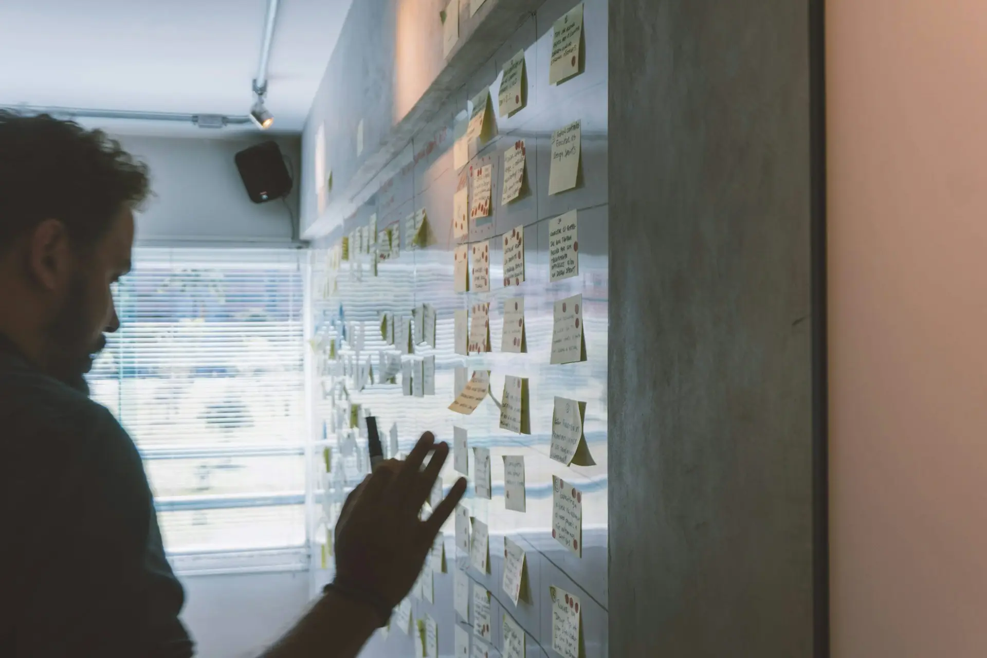 Team member mapping a workflow with sticky notes on a glass office wall