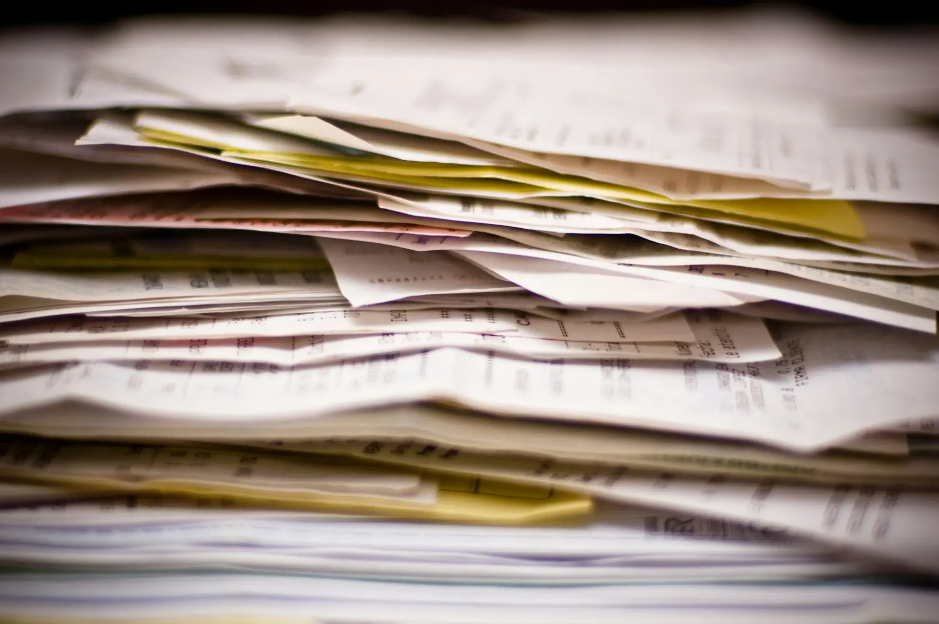 Thick stack of paper invoices and forms waiting to be processed by hand